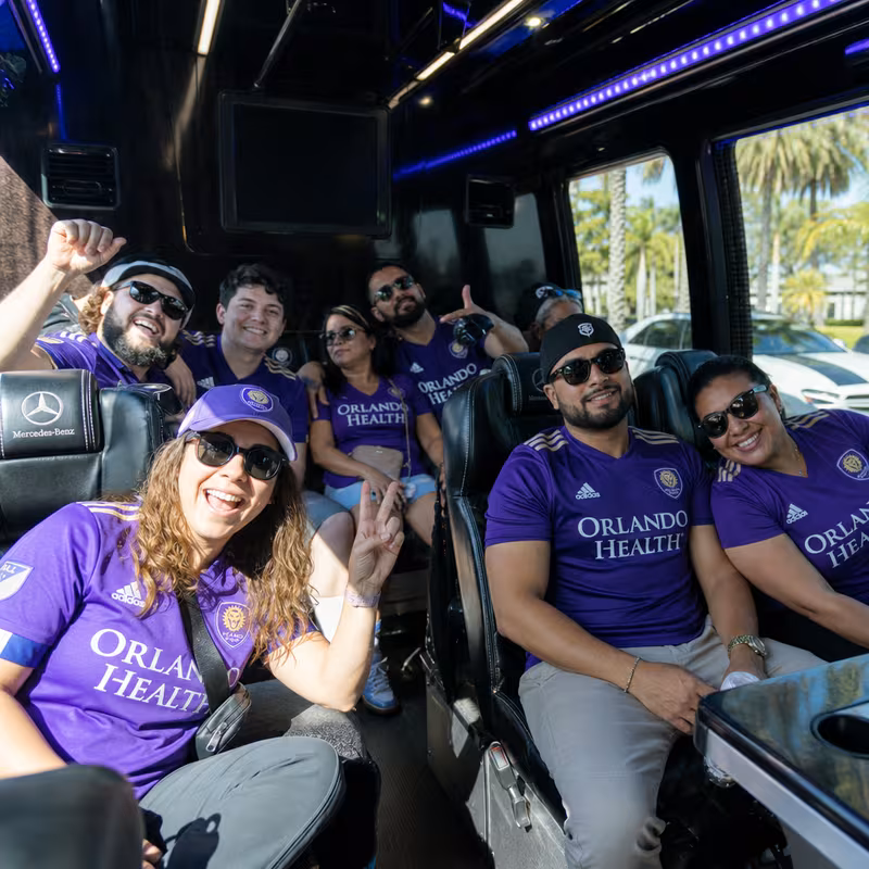 Group boarding a white charter bus for Sporting Event Transportation transportation in Orlando